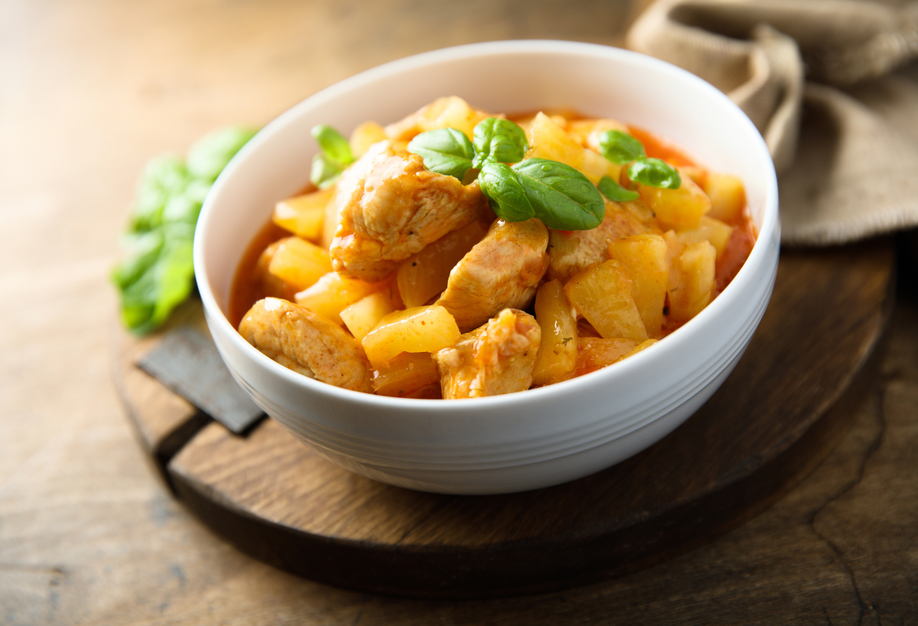 Hähnchencurry mit Ananas in einer weißen Schüssel mit Basilikum garniert