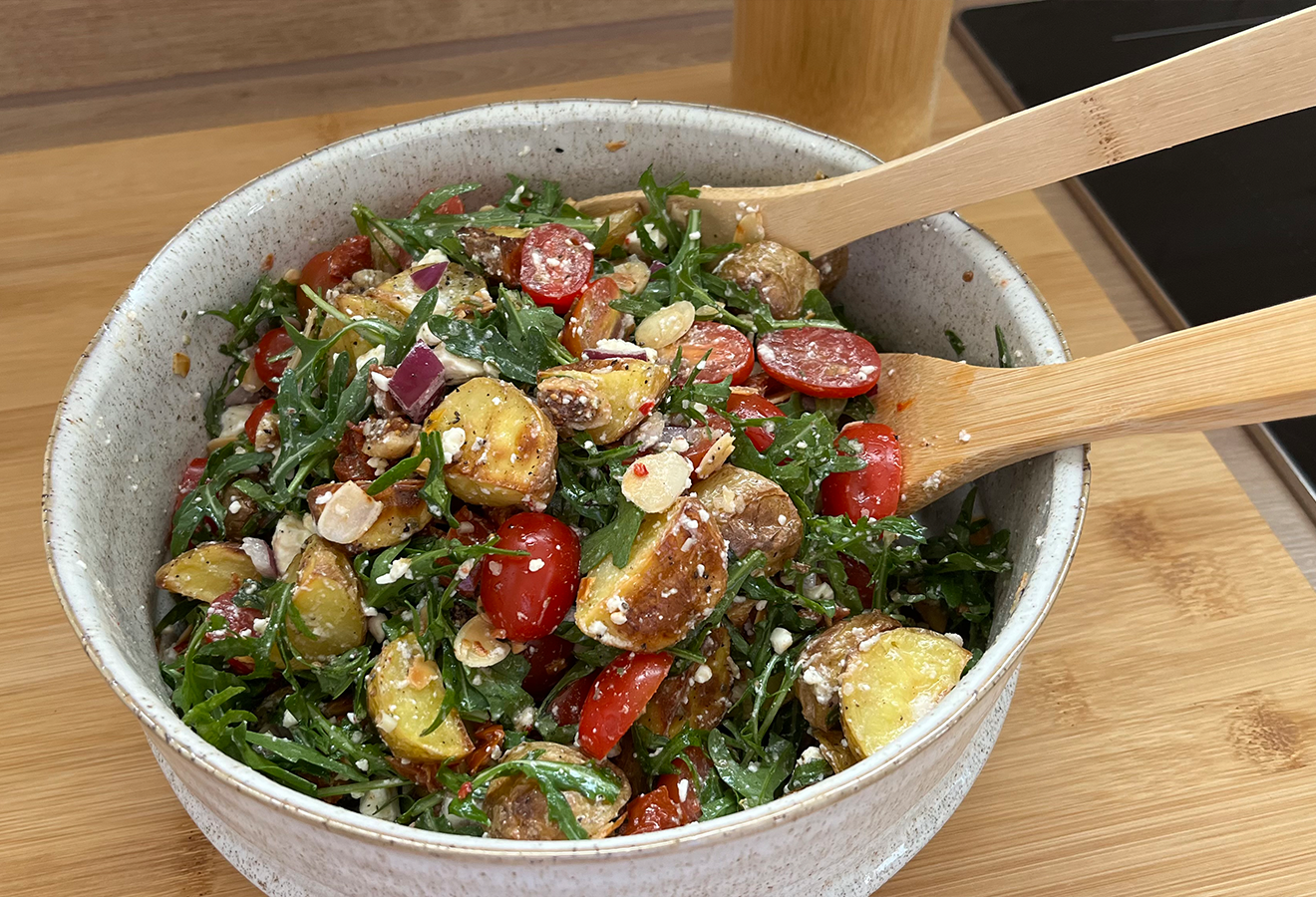 Mediterraner Kartoffelsalat in einer Schüssel mit Holzlöffeln darin