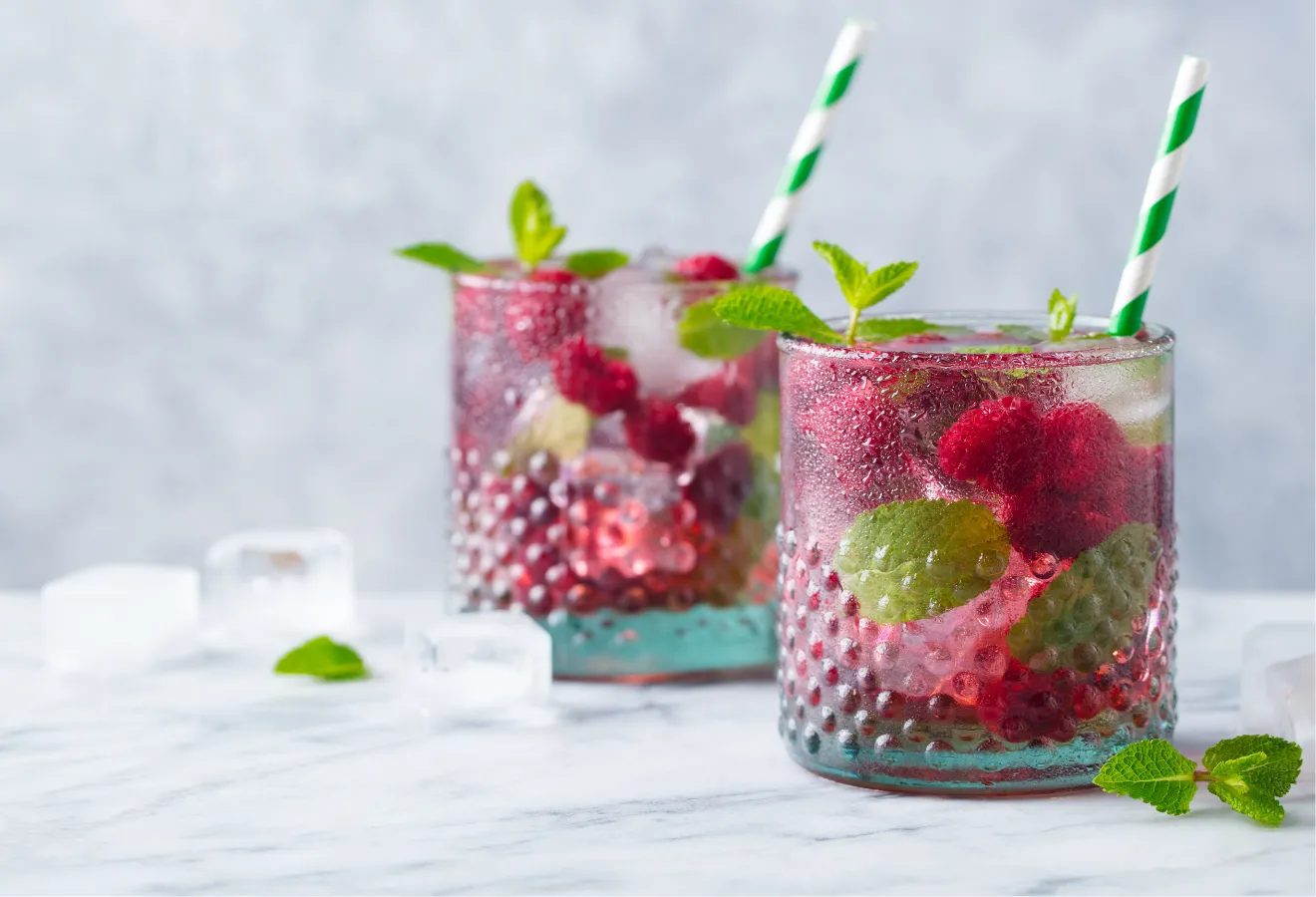 Eistee mit Beeren-Waldmeister mit Himbeeren und Minze in 2 Gläsern