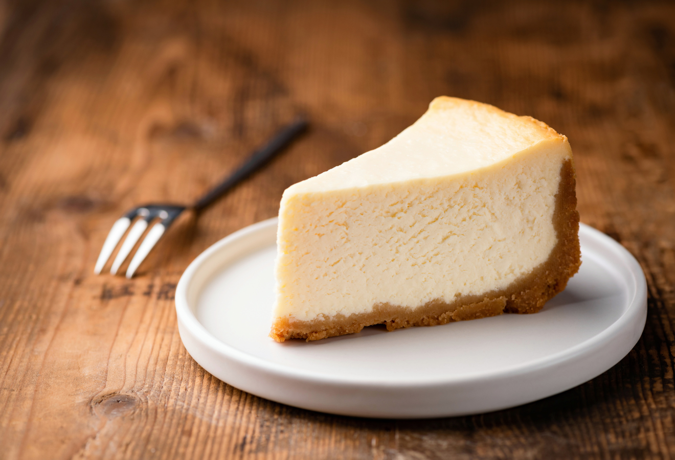 Winterliche Frischkäsetorte auf einem weißen Teller, im Hintergrund eine Gabel