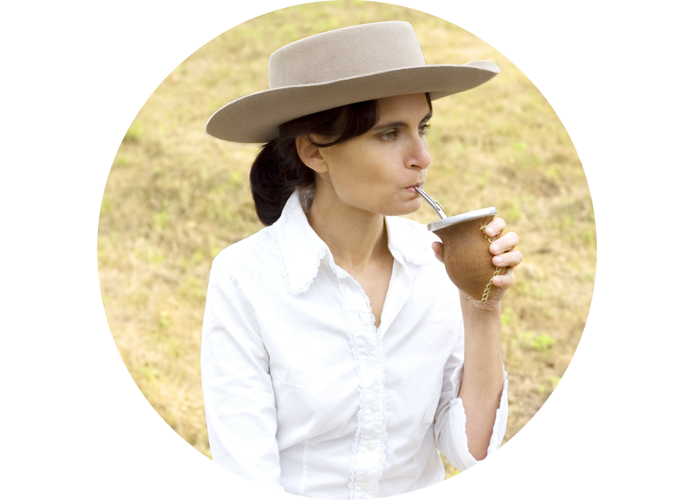 Frau mit Hut trinkt Mate-Tee aus einem traditionellen Gefäß mit Trinkröhrchen