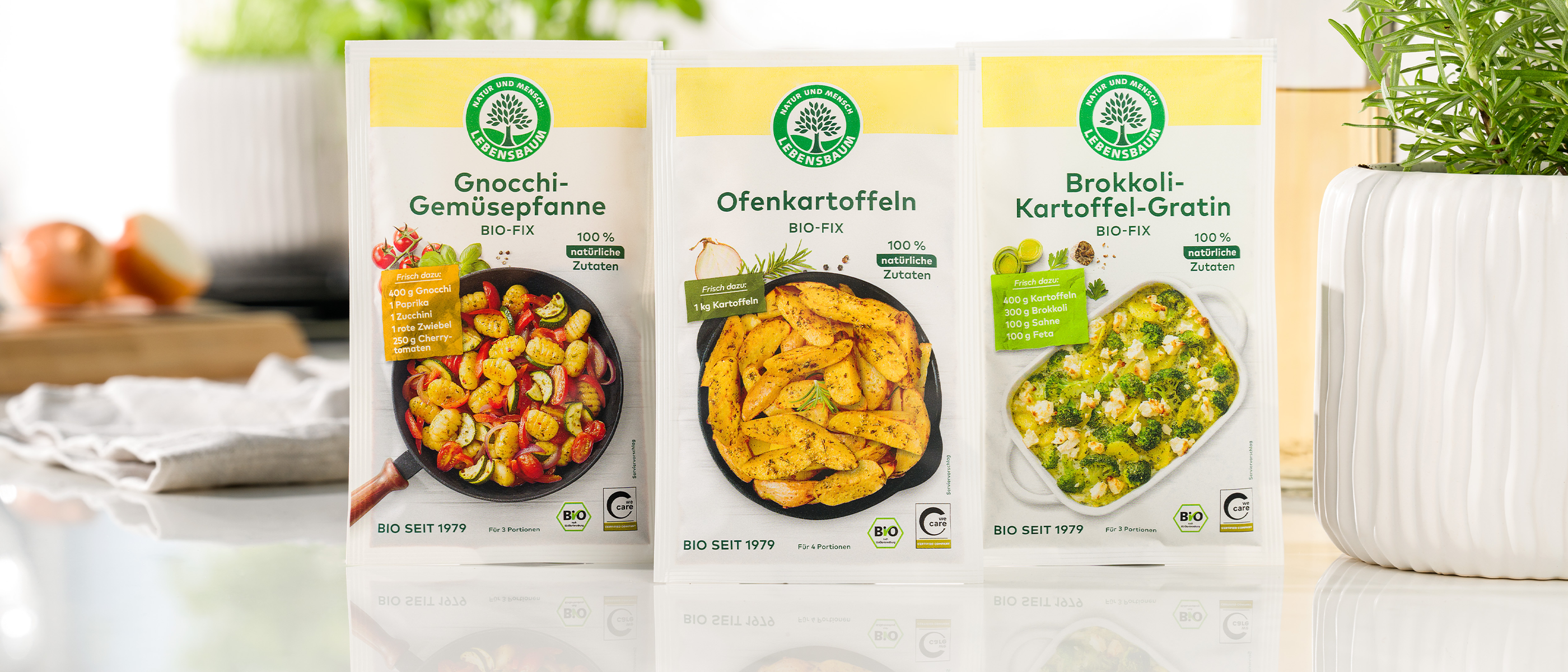 Drei Packungen Lebensbaum Bio-Fix-Gewürzmischungen für Gnocchi-Gemüsepfanne, Ofenkartoffeln und Brokkoli-Kartoffel-Gratin stehen nebeneinander auf einem hellen Küchentisch