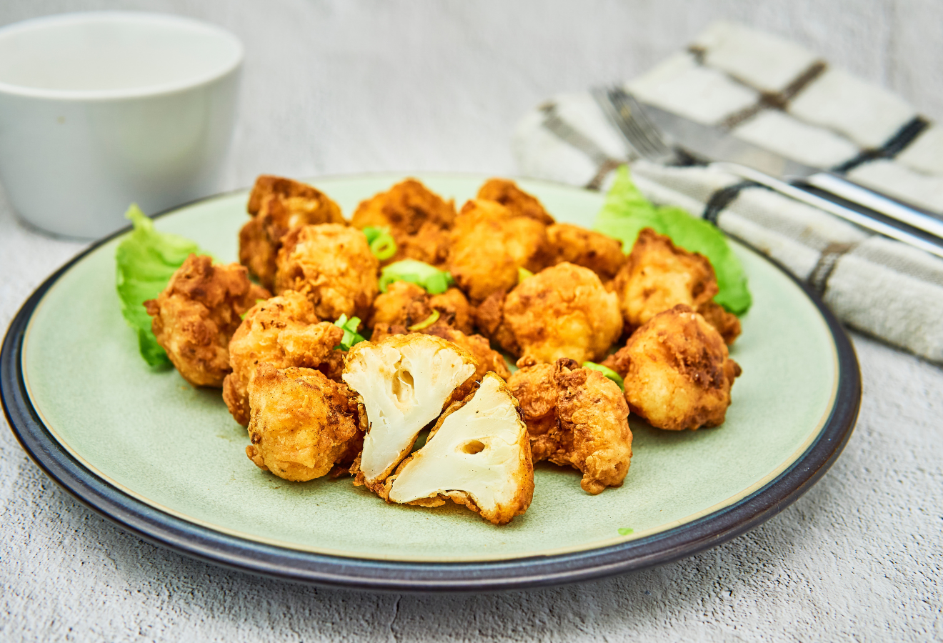Blumenkohl-Wings, vegan auf einem Teller mit Salatblättern dekoriert