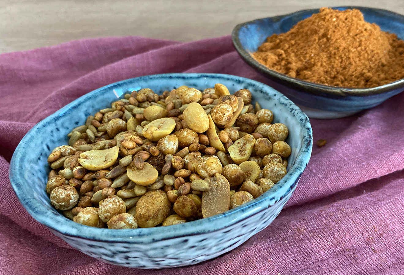 Gerösteter Getreidesnack "Kolo" in einer blauen schale, dahinter eine Schale mit Gewürzen