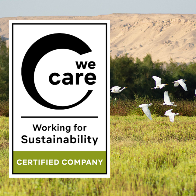 Weiße Vögel fliegen über eine grüne Wiese mit Bäumen im Hintergrund; daneben das Nachhaltigkeitssiegel ‚We Care´