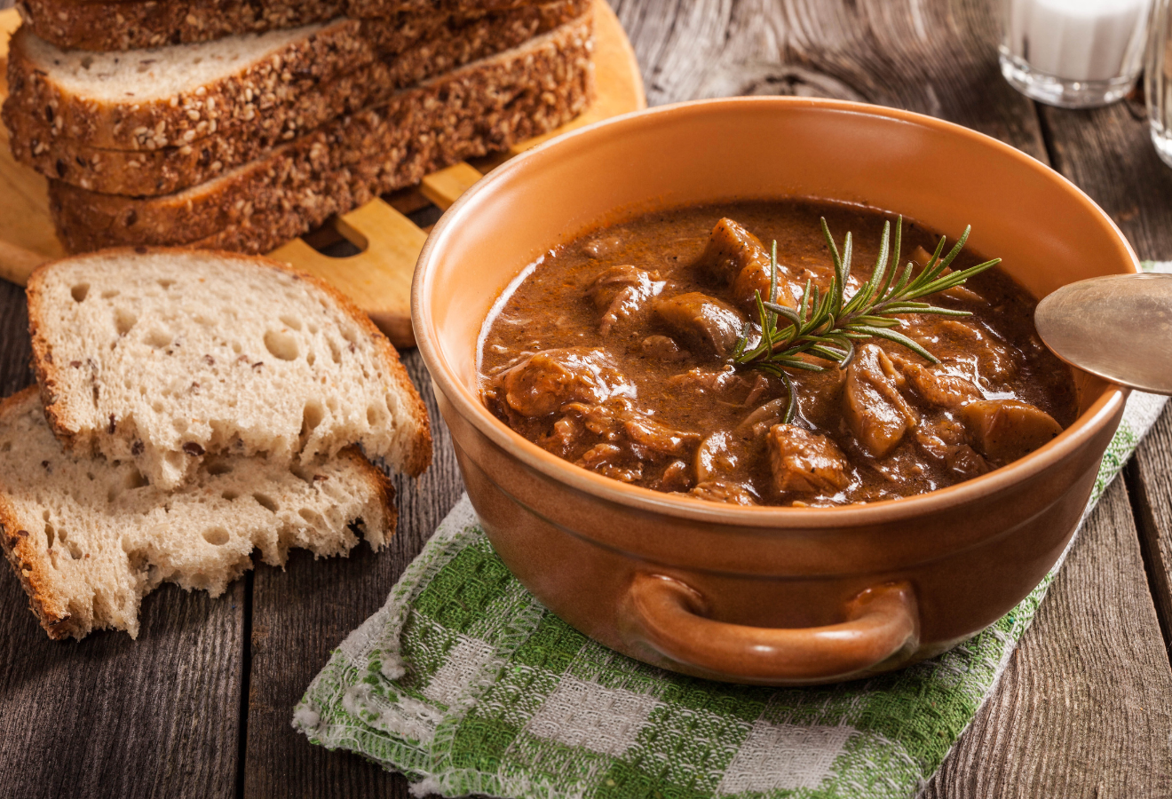 5-Gewürze-Gulasch in einem Topf mit Rosmarin an Brot dekoriert
