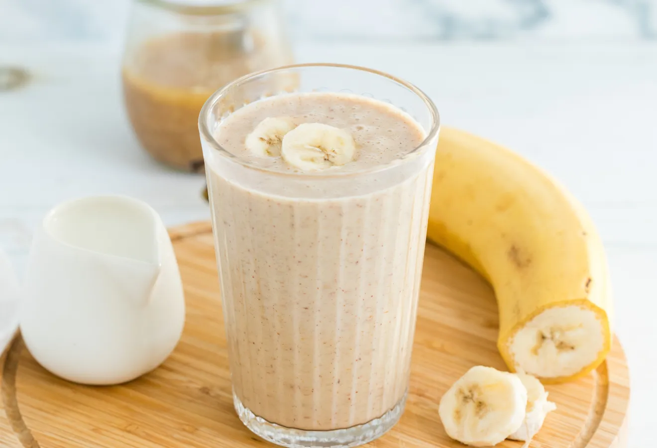 Rooibos Smoothie im Glas mit Bananenscheiben garniert und einer Banane daneben