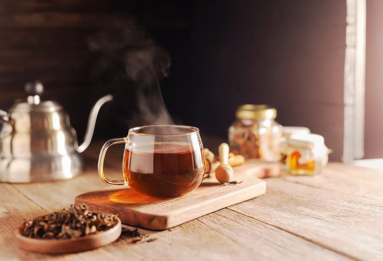 Tee mit Rum in einer Glastasse auf einem Holzbrett