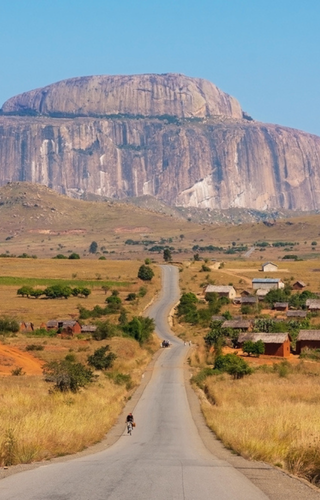 Lange Straße führt durch trockene Landschaft auf einen riesigen Tafelberg zu in Madagaskar