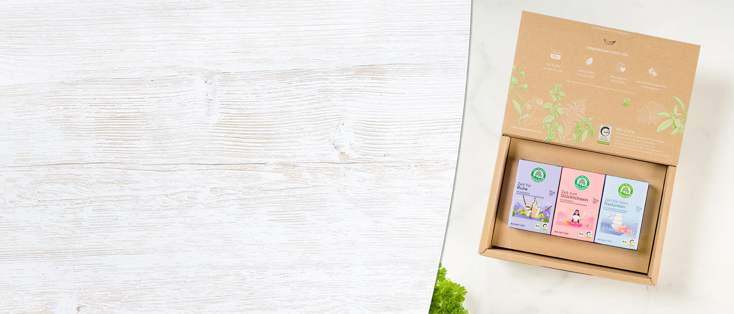 Tee-Geschenkset mit drei Sorten in Naturkarton-Box auf weißem Holzuntergrund, Teemischungen für Ruhe, Glücklichsein und Meditation